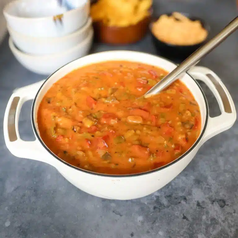 Large batch of green chile stew in a cast iron pot.