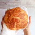 Baked loaf of bread held up by two hands.