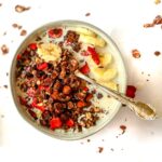 Dark chocolate granola in a bowl with oat milk and sliced bananas.