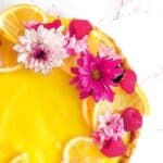 Lemon tart decorated with lemons, raspberries and flowers.