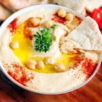 A bowl of hummus with paprika, olive oil and garbanzo beans.