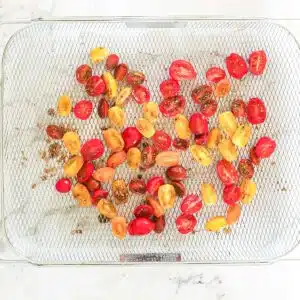 Tomatoes halved and on an air fryer basket.