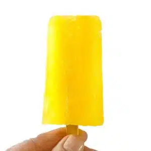 A hand holding up a bright yellow lemonade popsicle.