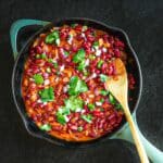Picture of lubya in a skillet garnished with cilantro and a wooden spoon.
