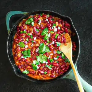 Picture of lubya in a skillet garnished with cilantro and a wooden spoon.
