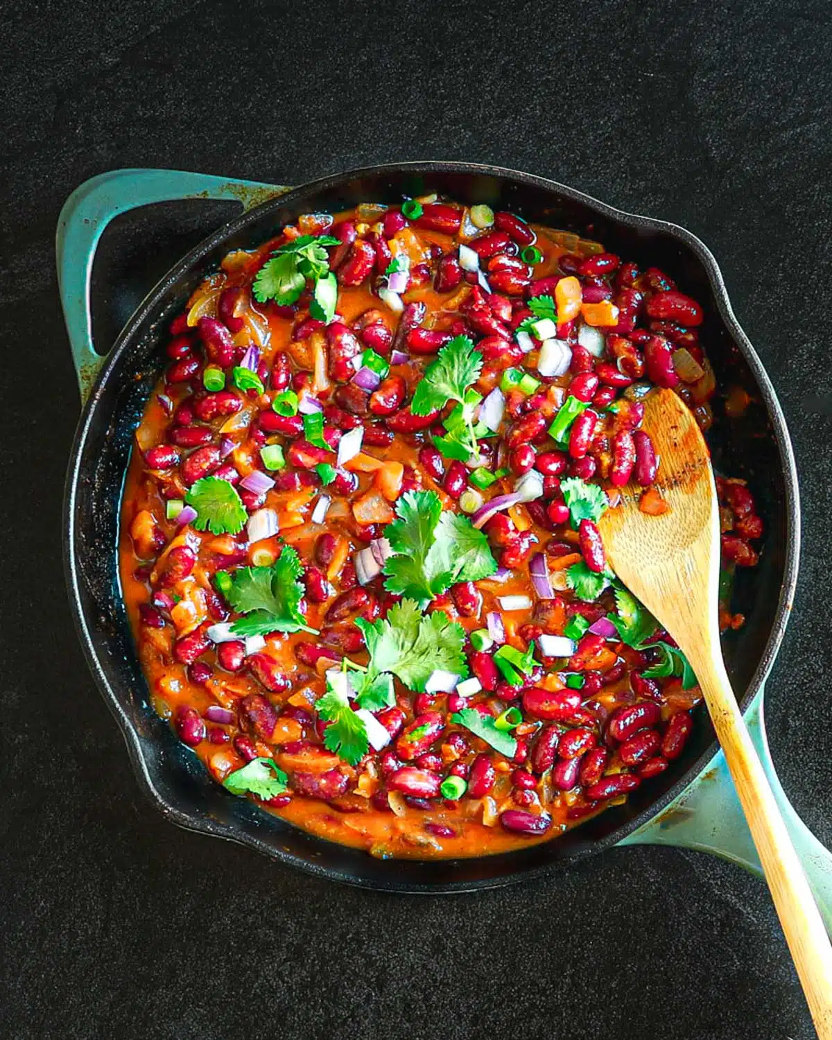 Picture of lubya in a skillet garnished with cilantro and a wooden spoon.