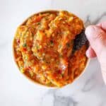 Hand dipping a chip into mango habanero salsa.
