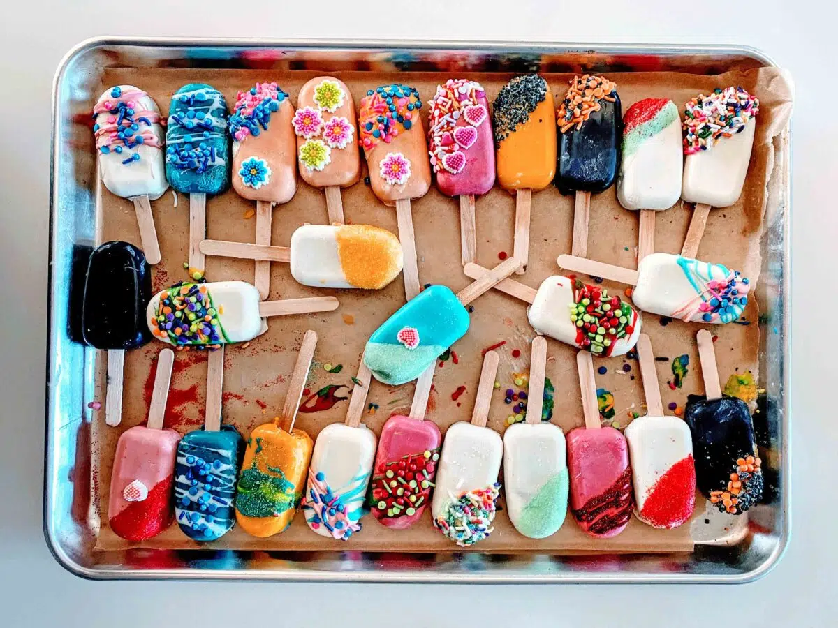 A tray full of various decorated  cakesicles