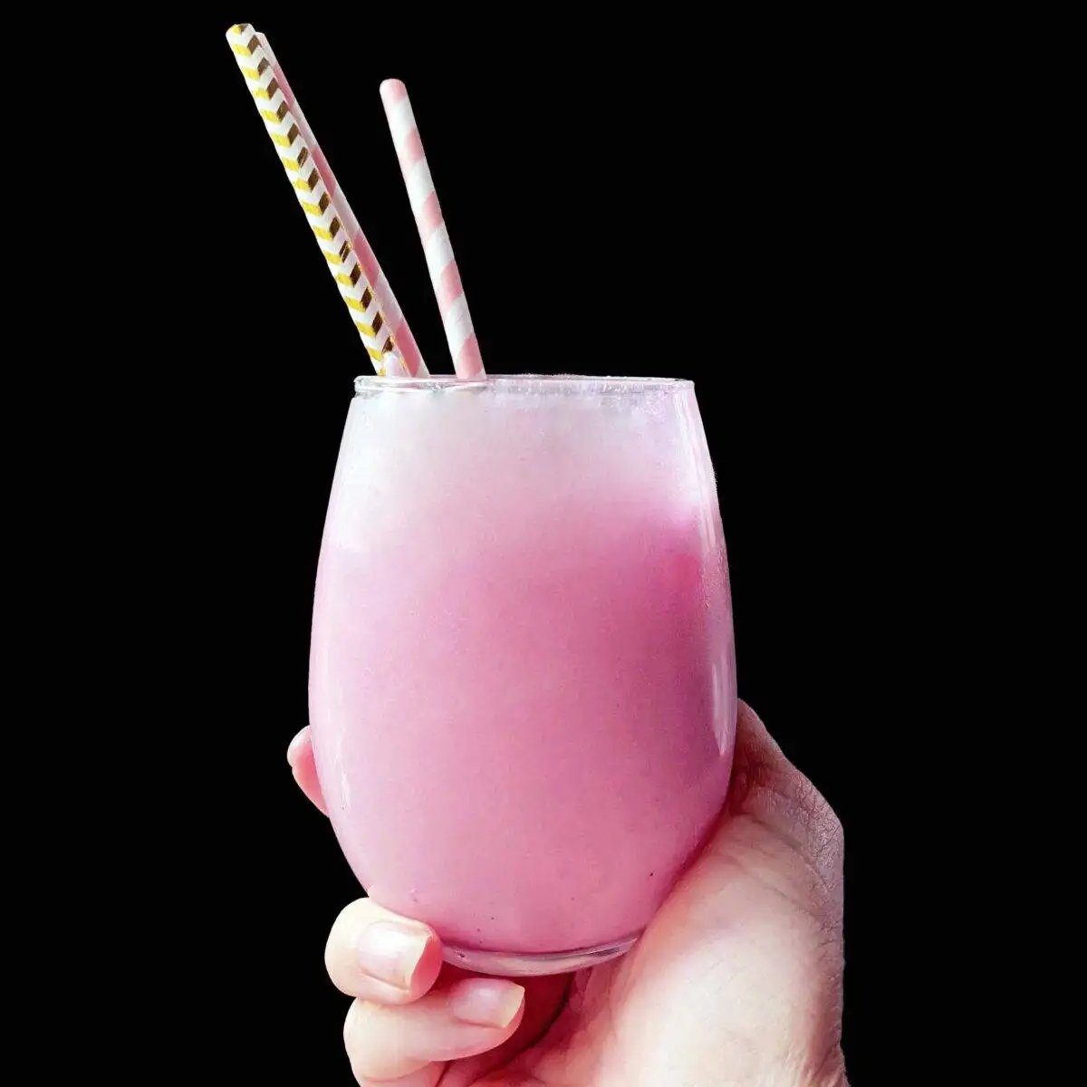 Hand holding up drink with black background.