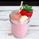 Angel food smoothie in a glass garnished with a strawberry and banana.