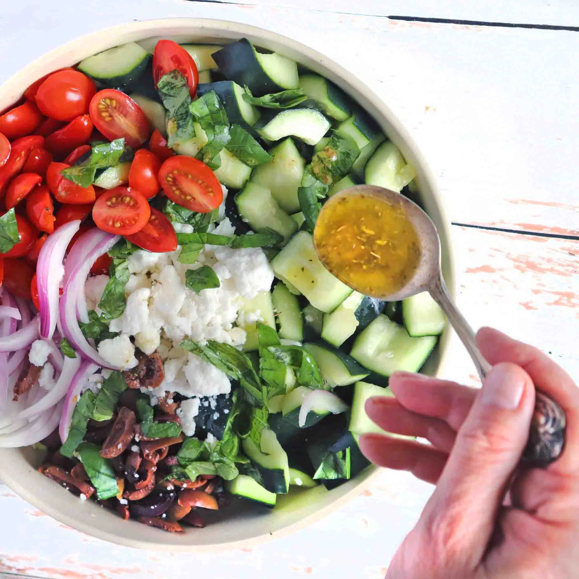 Dressing being spooned onto the salad.