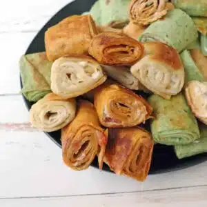 Pilled grilled cream cheese pinwheels stacked on a plate.