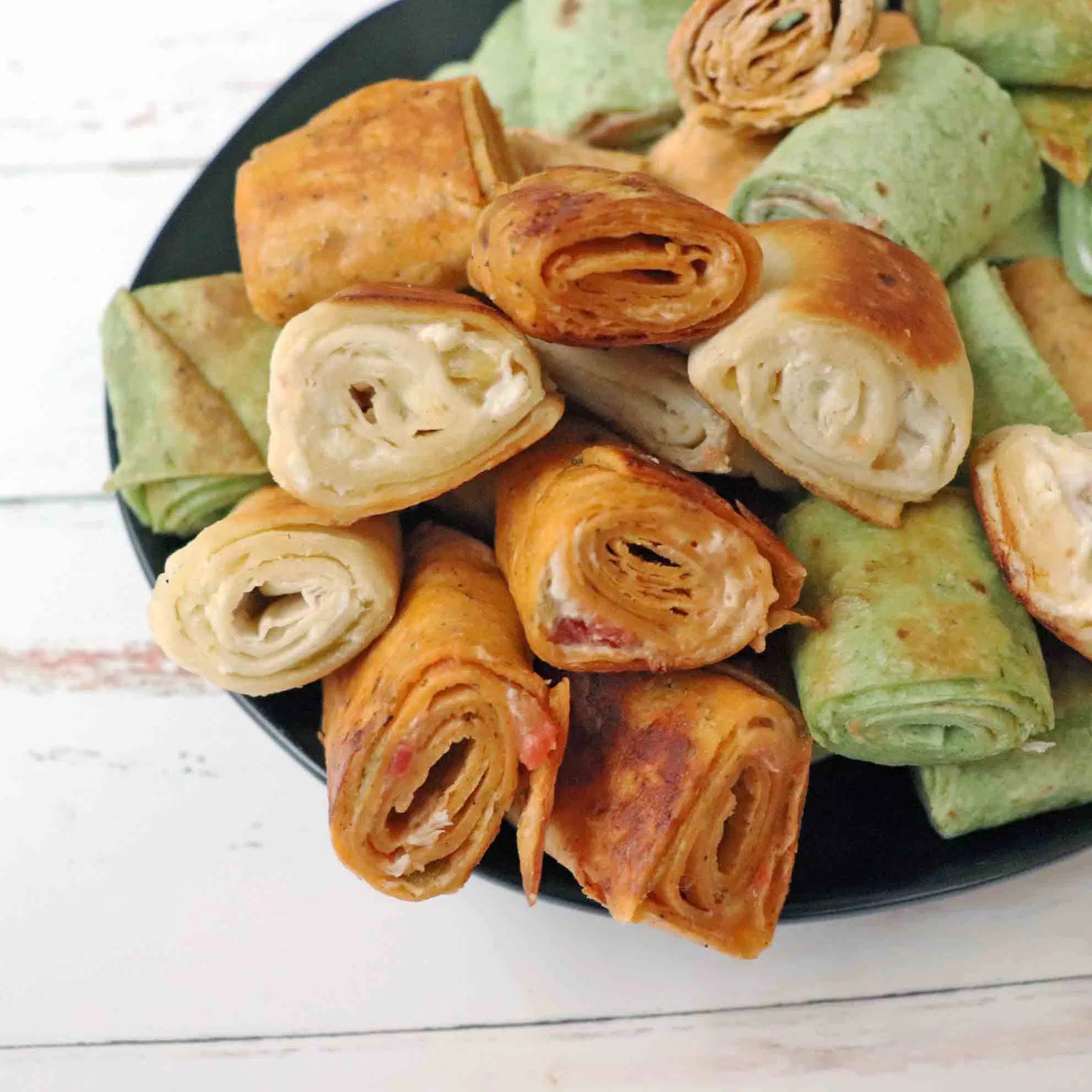 Pilled grilled cream cheese pinwheels stacked on a plate.