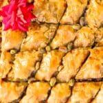 Pistachio baklava in a tray with a red rose on top.