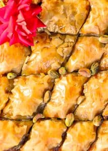 Pistachio baklava in a tray with a red rose on top.