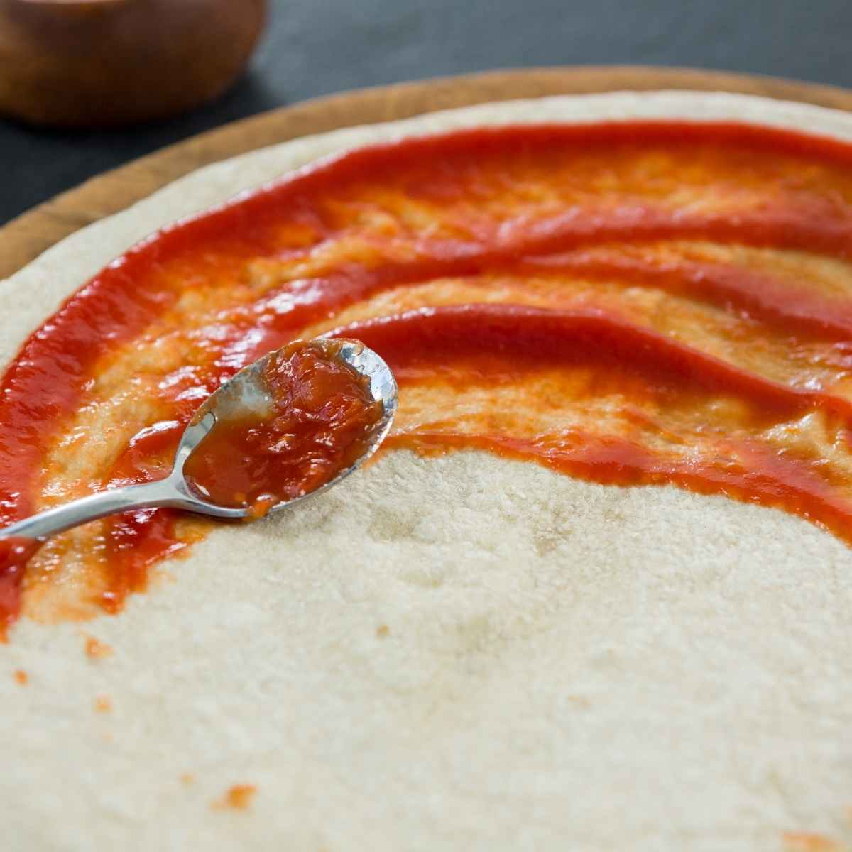 Raw pizza dough with tomato sauce.