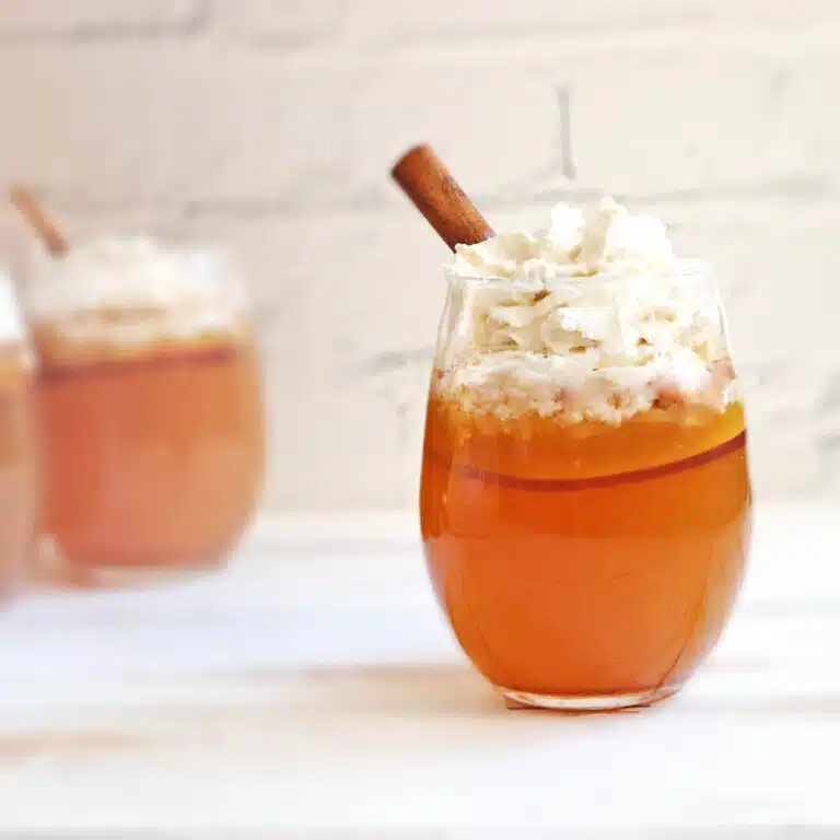 Cocktail garnished with whipped cream and a cinnamon stick.