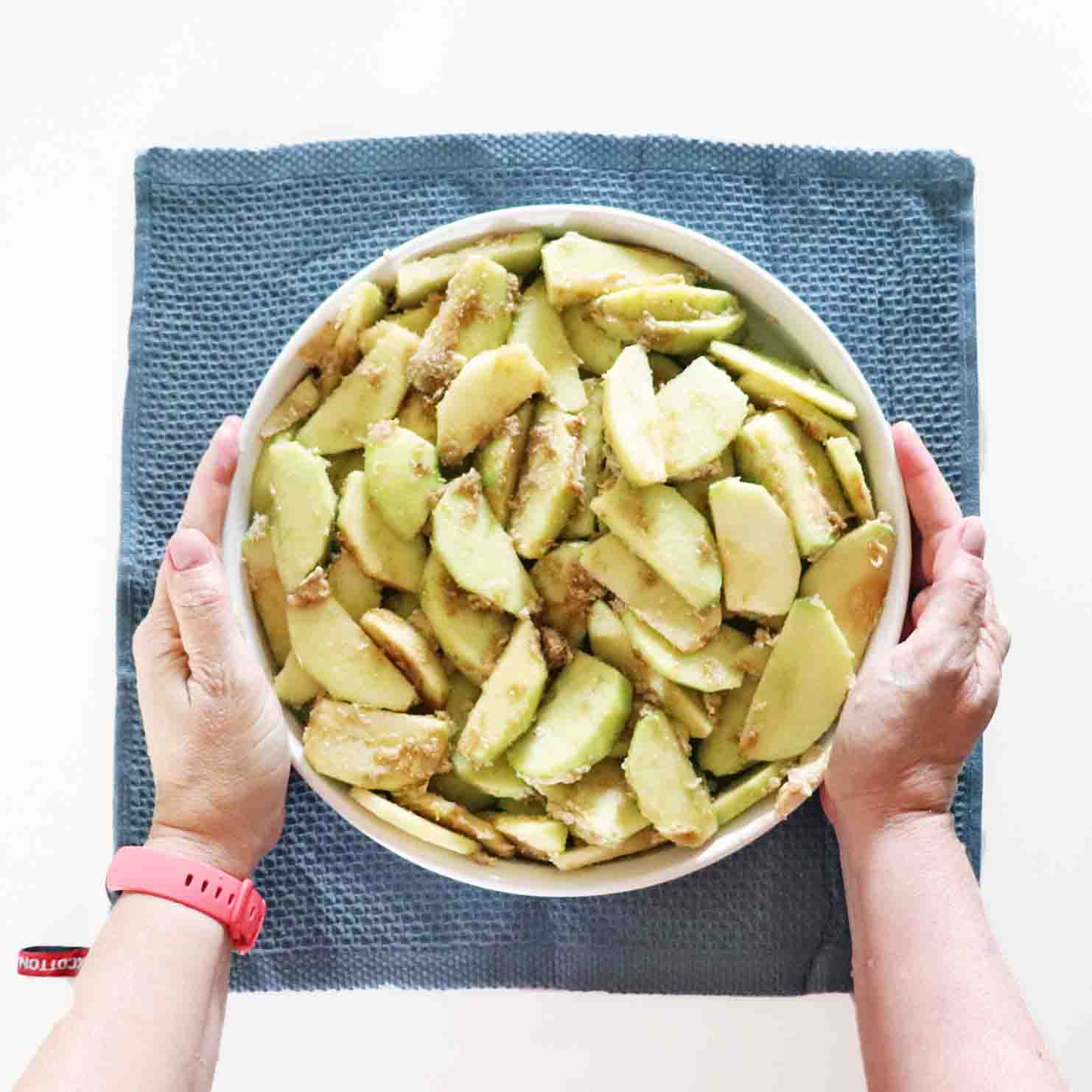 Prepared apples in a dish topped with brown sugar.