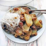 Apple crumble serving on a plate with vanilla ice cream.