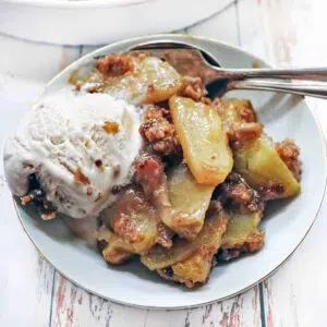 Apple crumble serving on a plate with vanilla ice cream.