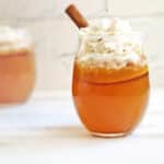 Cocktail garnished with whipped cream and a cinnamon stick.