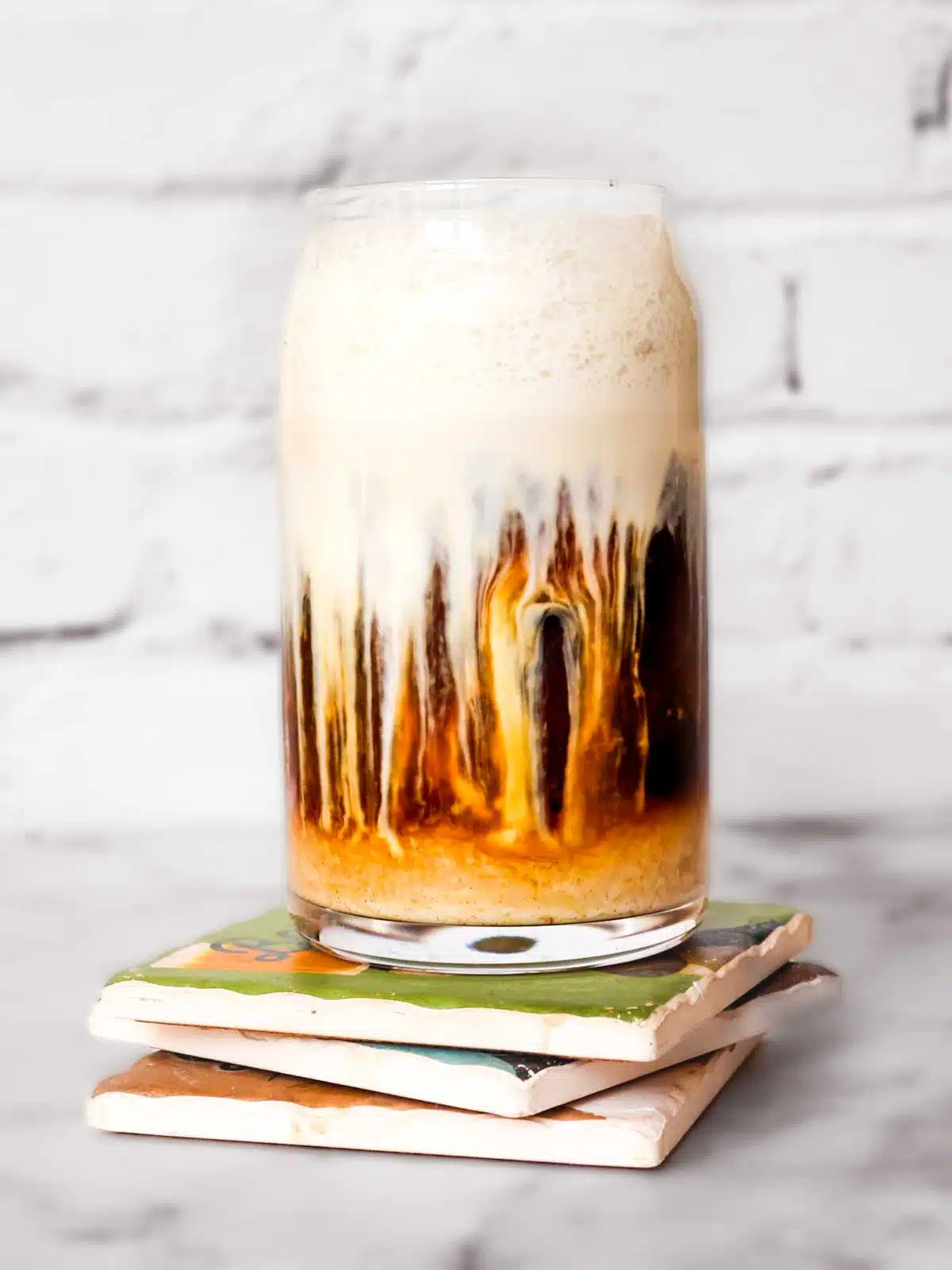 Sweet cream cold foam blending into an iced coffee.