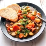 A bowl of stew with bread.