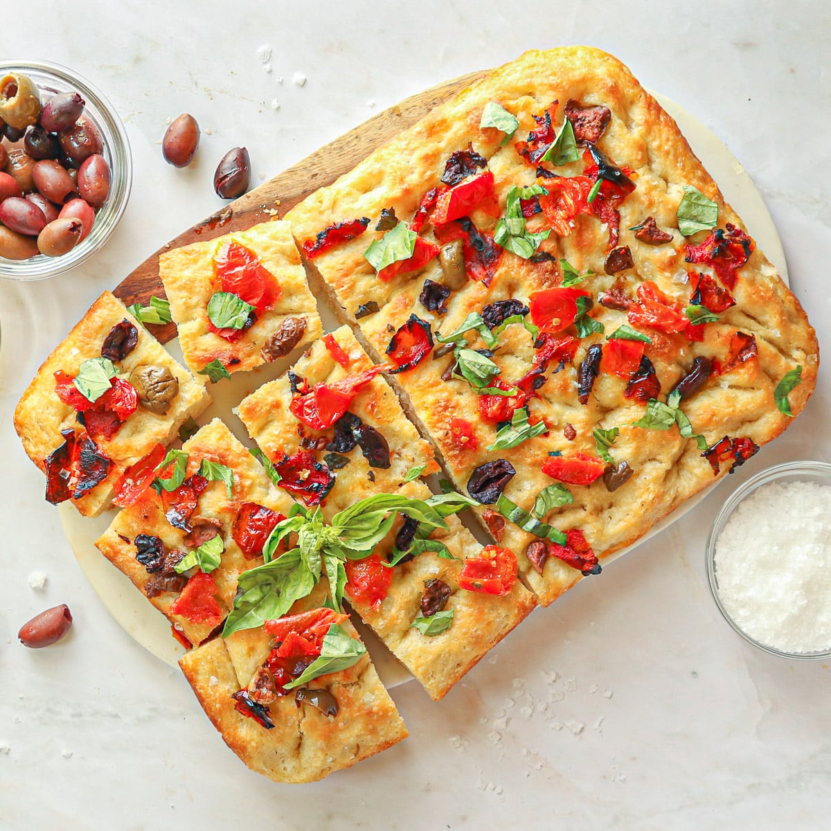 Focaccia bread topped with olives, basil and tomatoes.