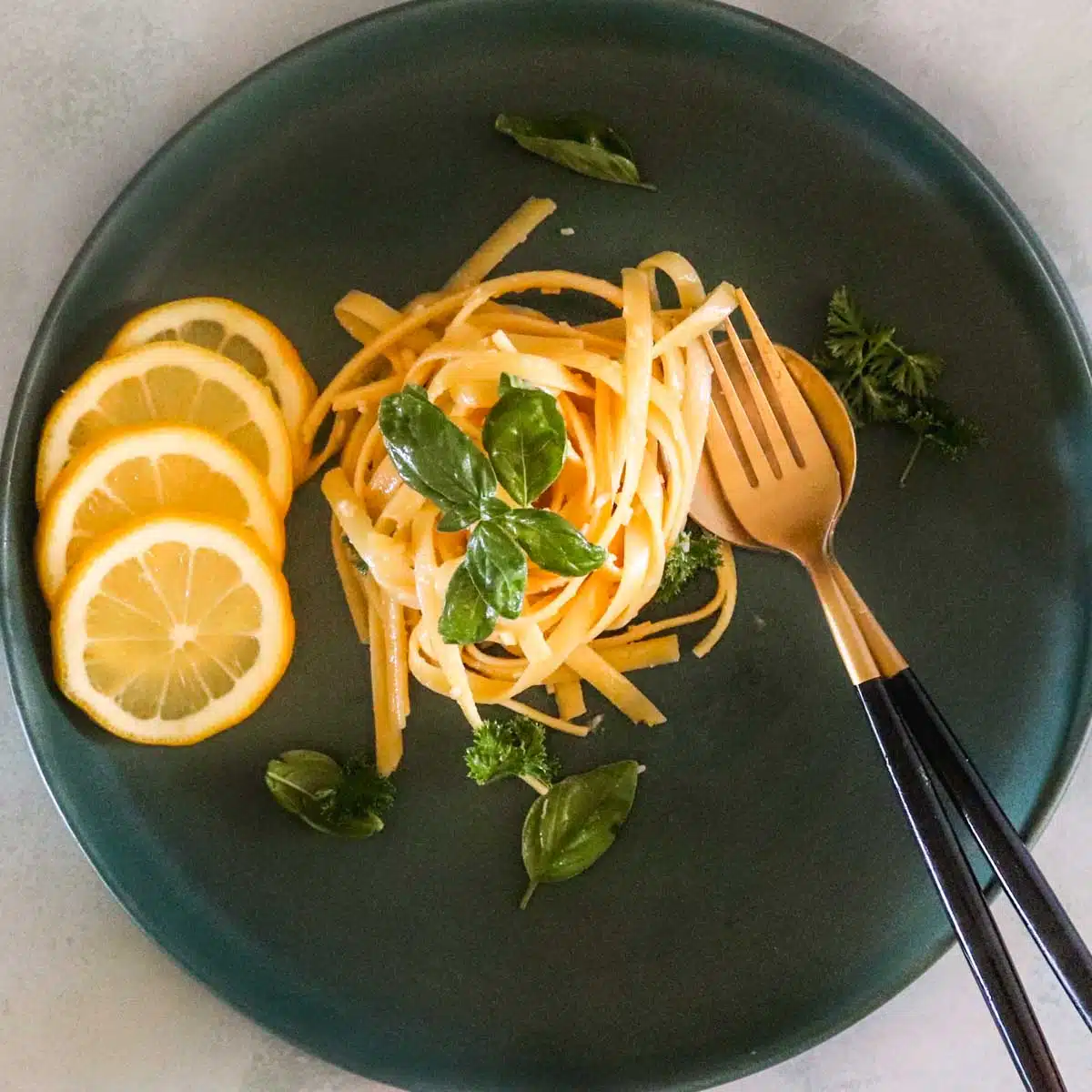 Plated dish garnished with lemons, basil and parsley. 