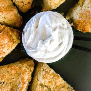 A plate of vegan scones with a small bowl of vegan clotted cream in the middle.