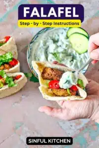 Spooning on tzatziki onto falafel in a pita pocket.