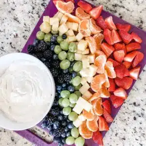 Platter filled with fruits arranged in a rainbow and the dip.