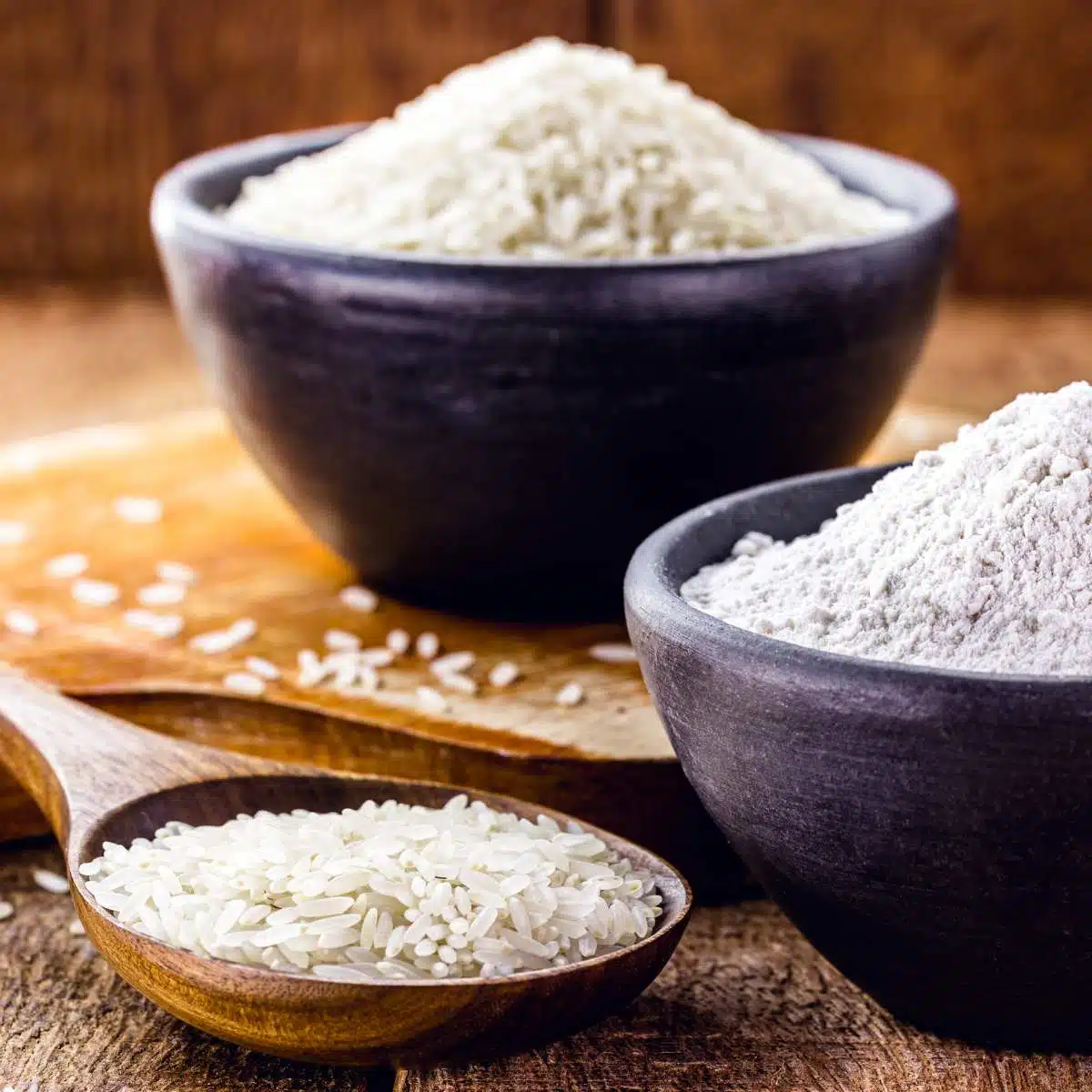 Rice in a spoon next to a bowl of rice flour. 