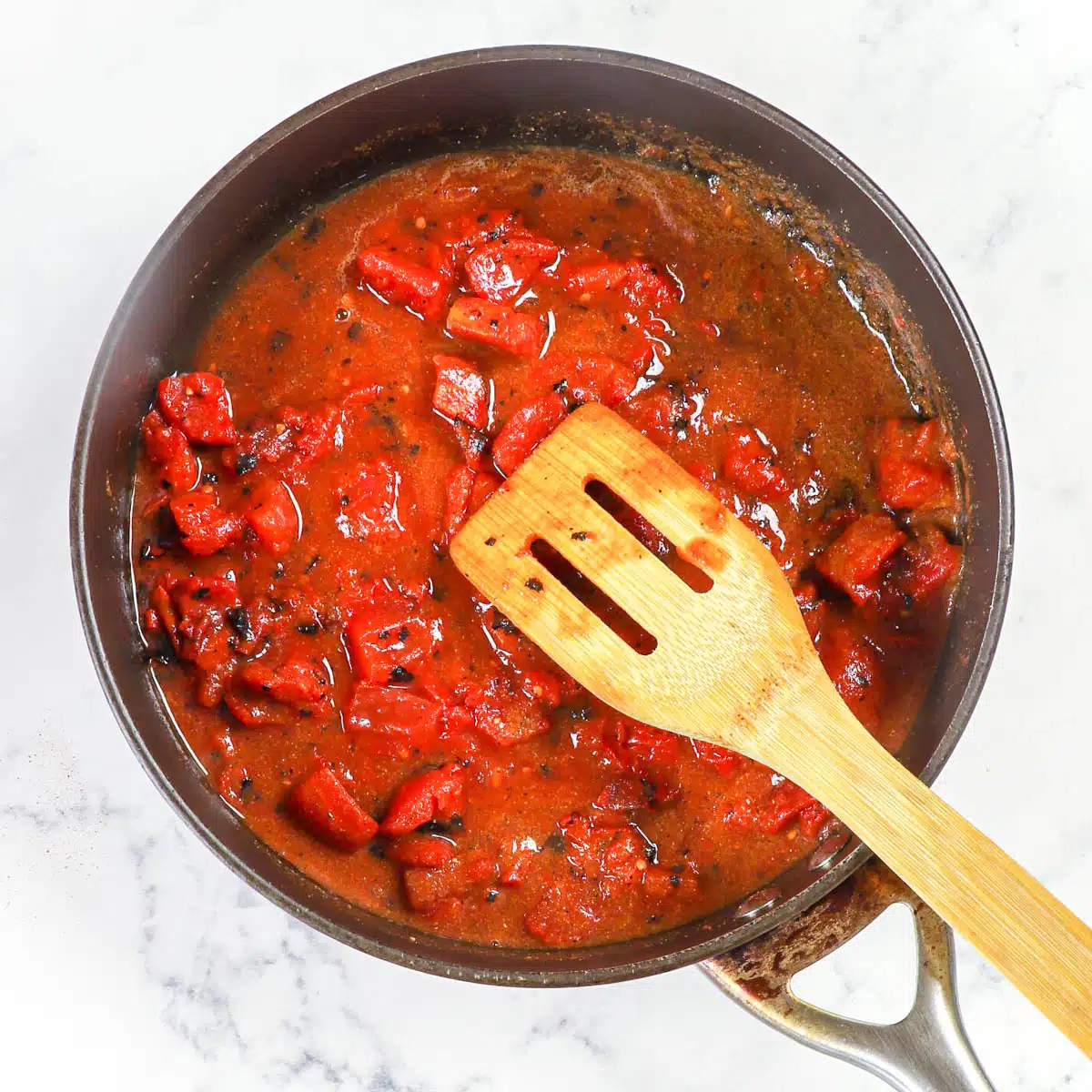 Tomatoes and spices simmering in a skillet.