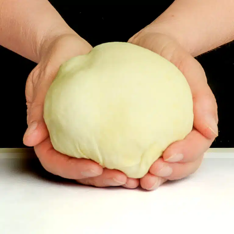 Raw pizza dough cupped in hands.