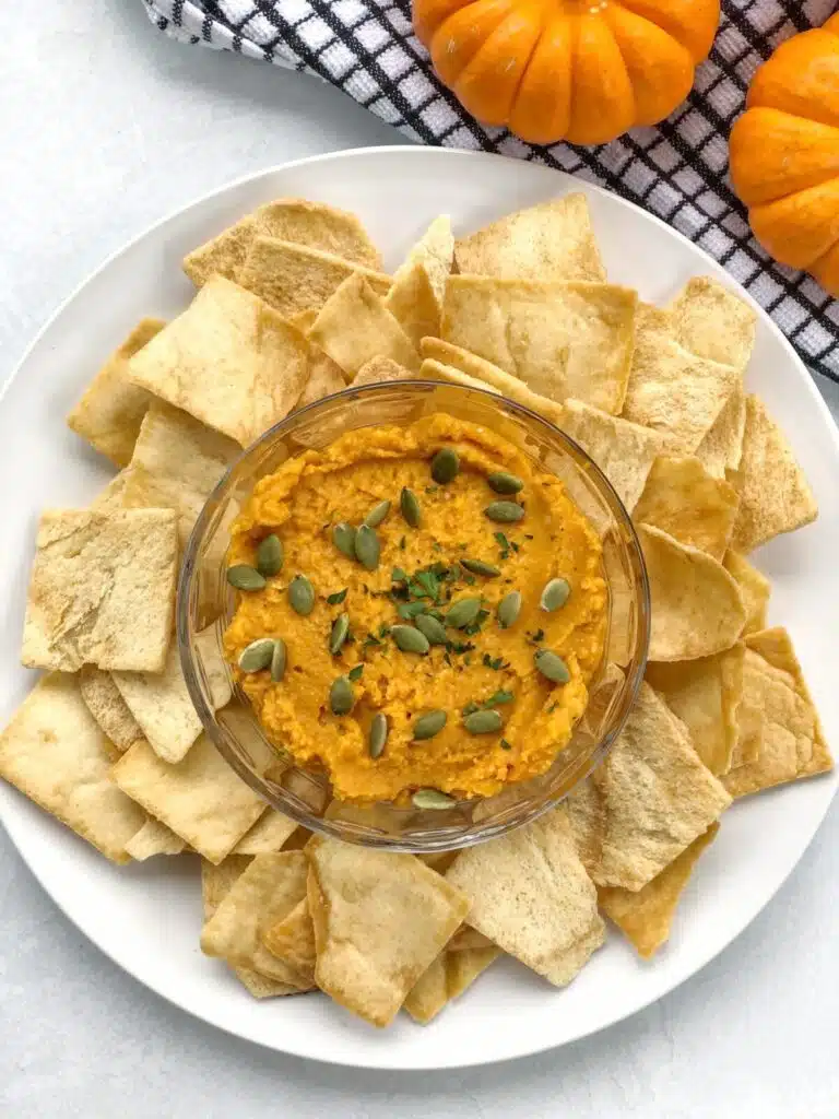Hummus in a bowl surrounded by pita chips.