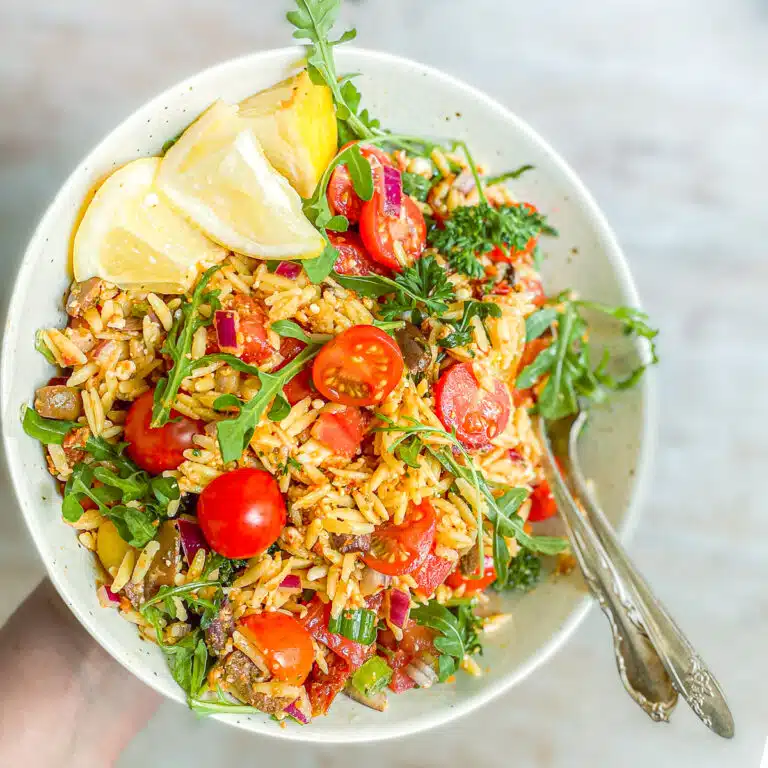 Hand holding a bowl of orzo.