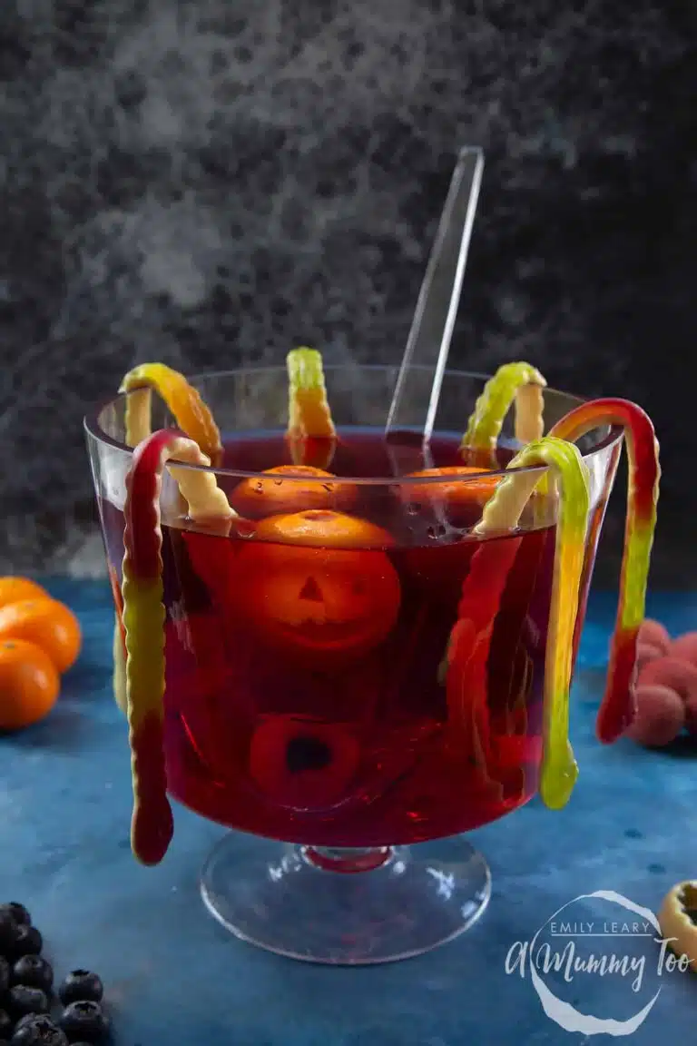 A bowl of punch with worms hanging off the sides. 
