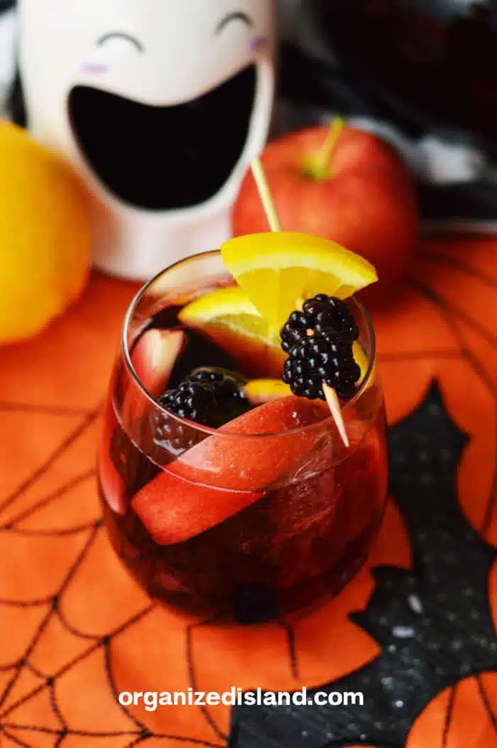 Cocktail on a spider napkin garnished with fruits. 