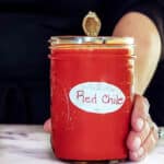 Hand holding a jar of New Mexico red chile in a mason jar.