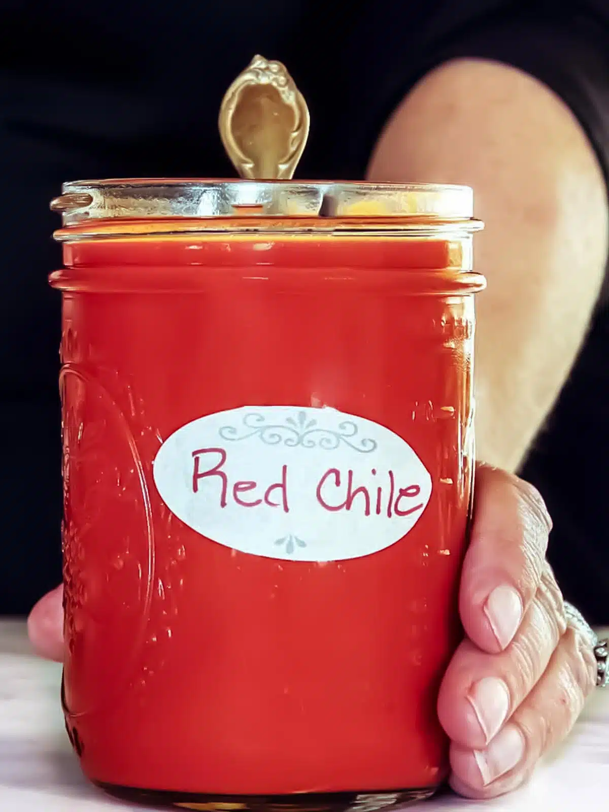 Hand holding a jar of New Mexico red chile in a mason jar.