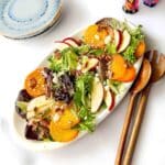 Golden beet salad on a platter with spoons.