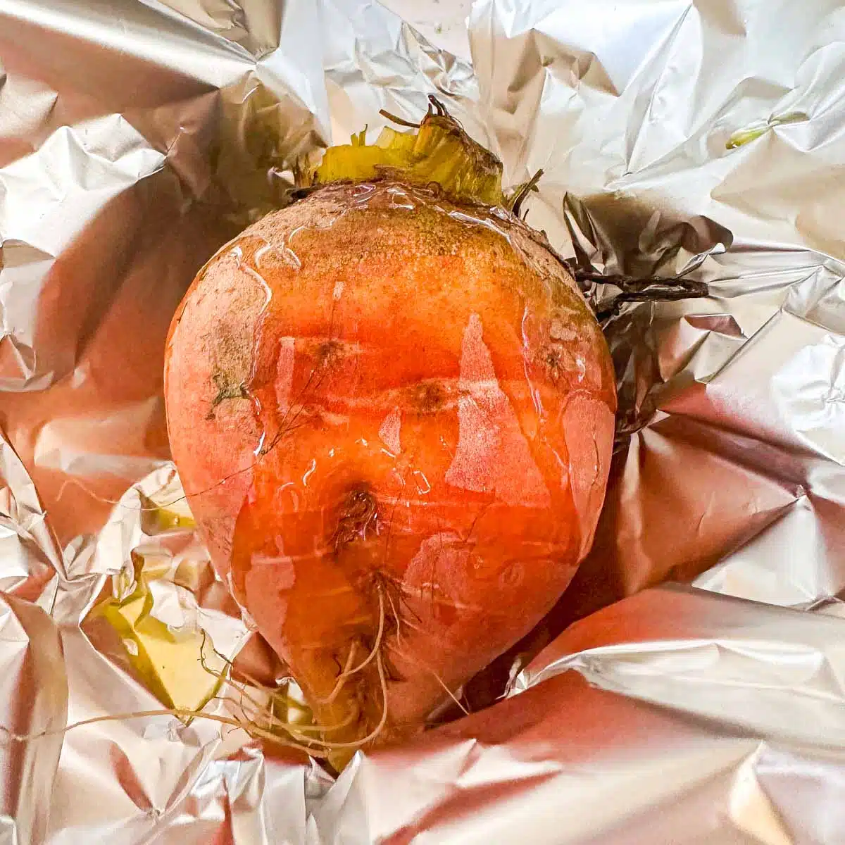 Golden beet in tin foil with oil poured on top. 