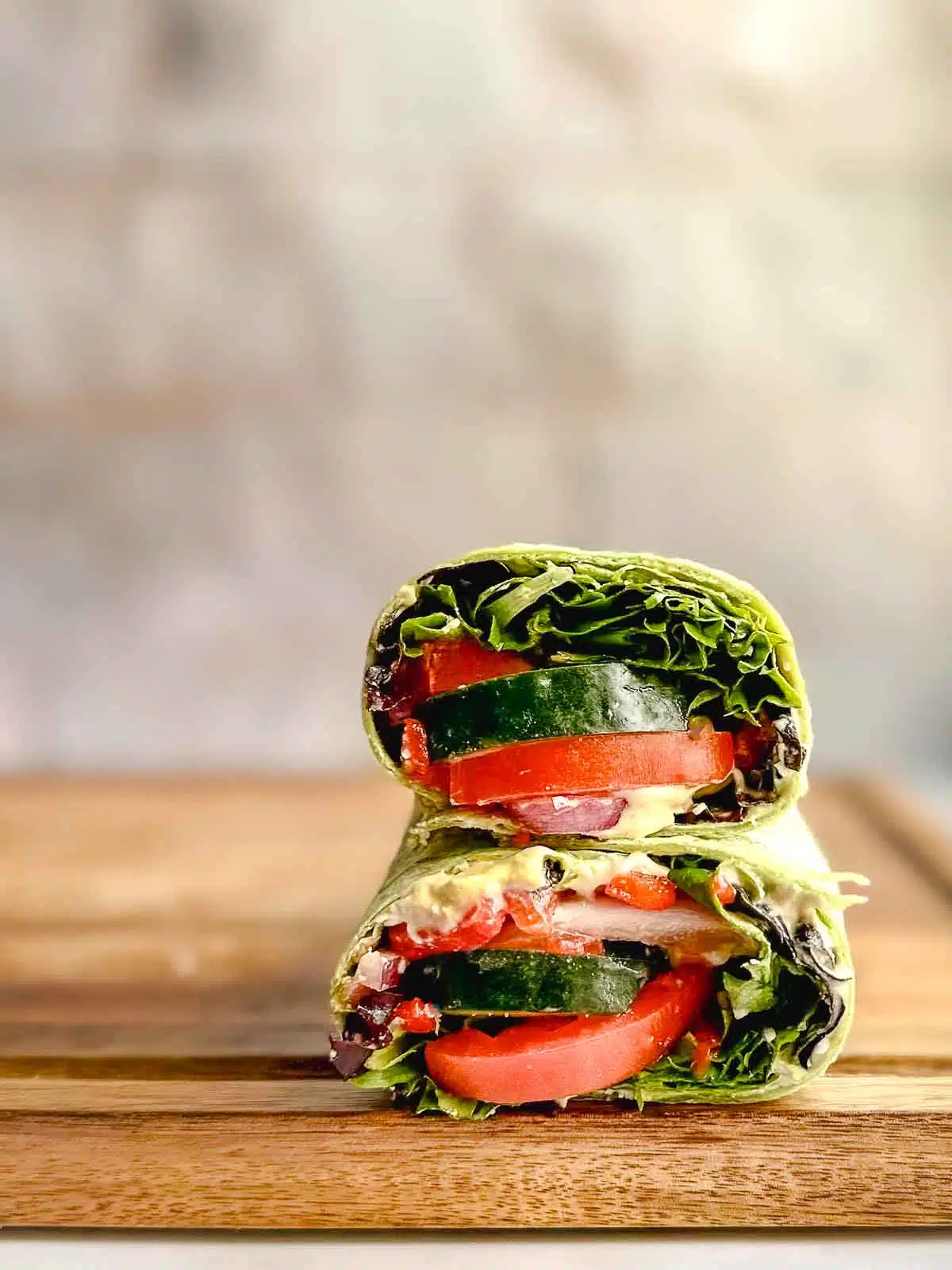 Two halves of a Mediterranean hummus wrap stacked on top of each other. 