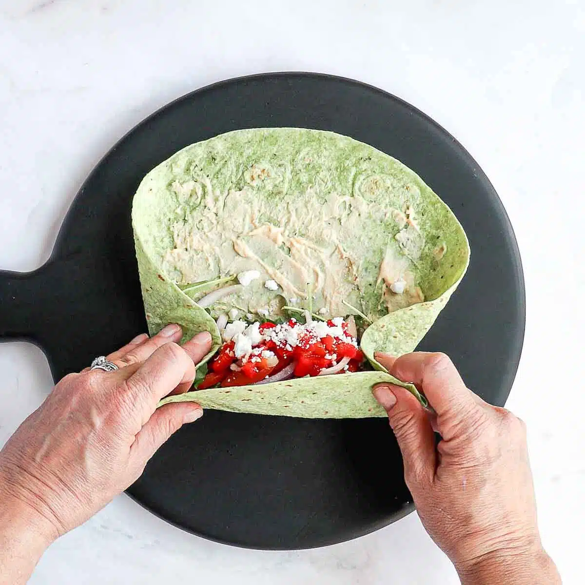 Two hands pulling the bottom of the tortilla over the top.