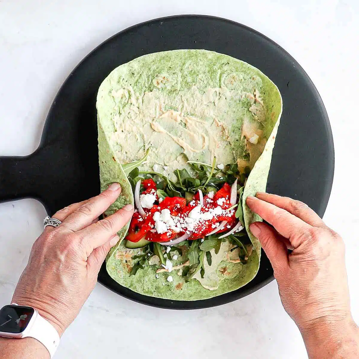 Two hands tucking in the sides of the wrap. 