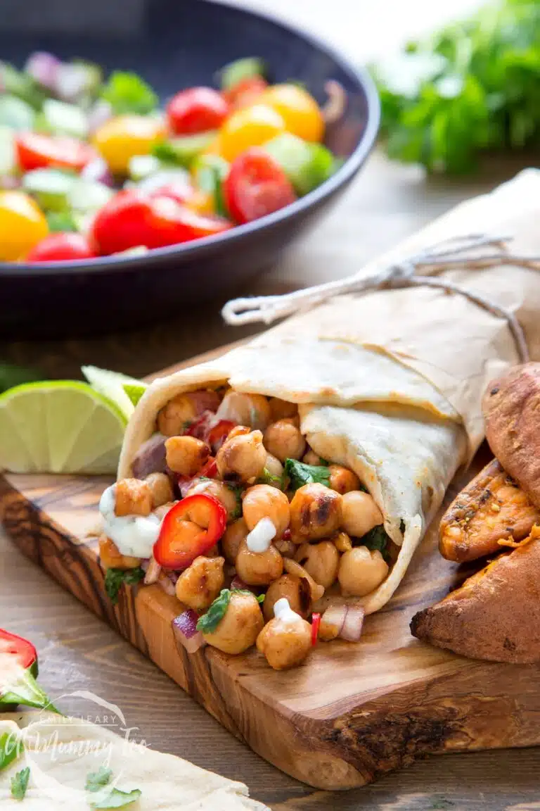 Wrap on a cutting board with chickpeas spilling out. 