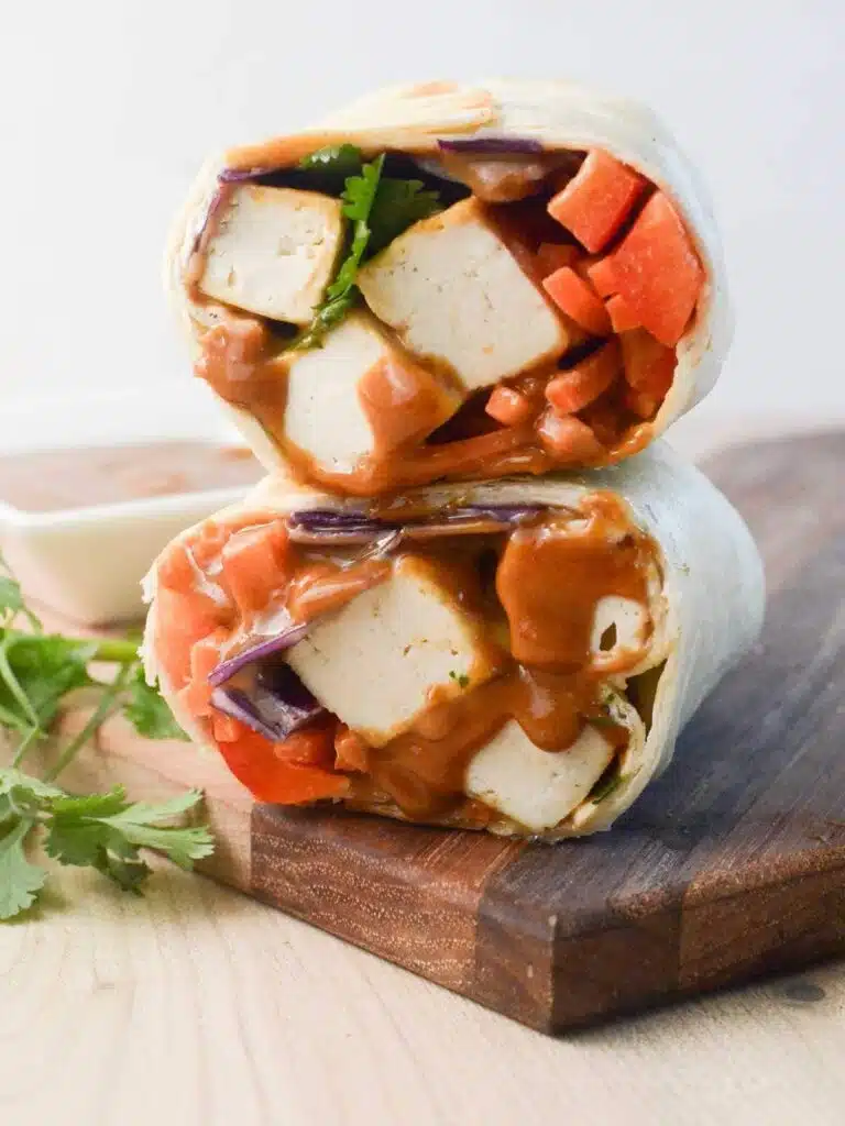 Two wraps stacked on top of each other on top of a cutting board.