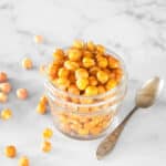Crispy chickpeas in a small jelly jar with a spoon near by.