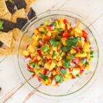 Pineapple and mango salsa with chips scattered around it.